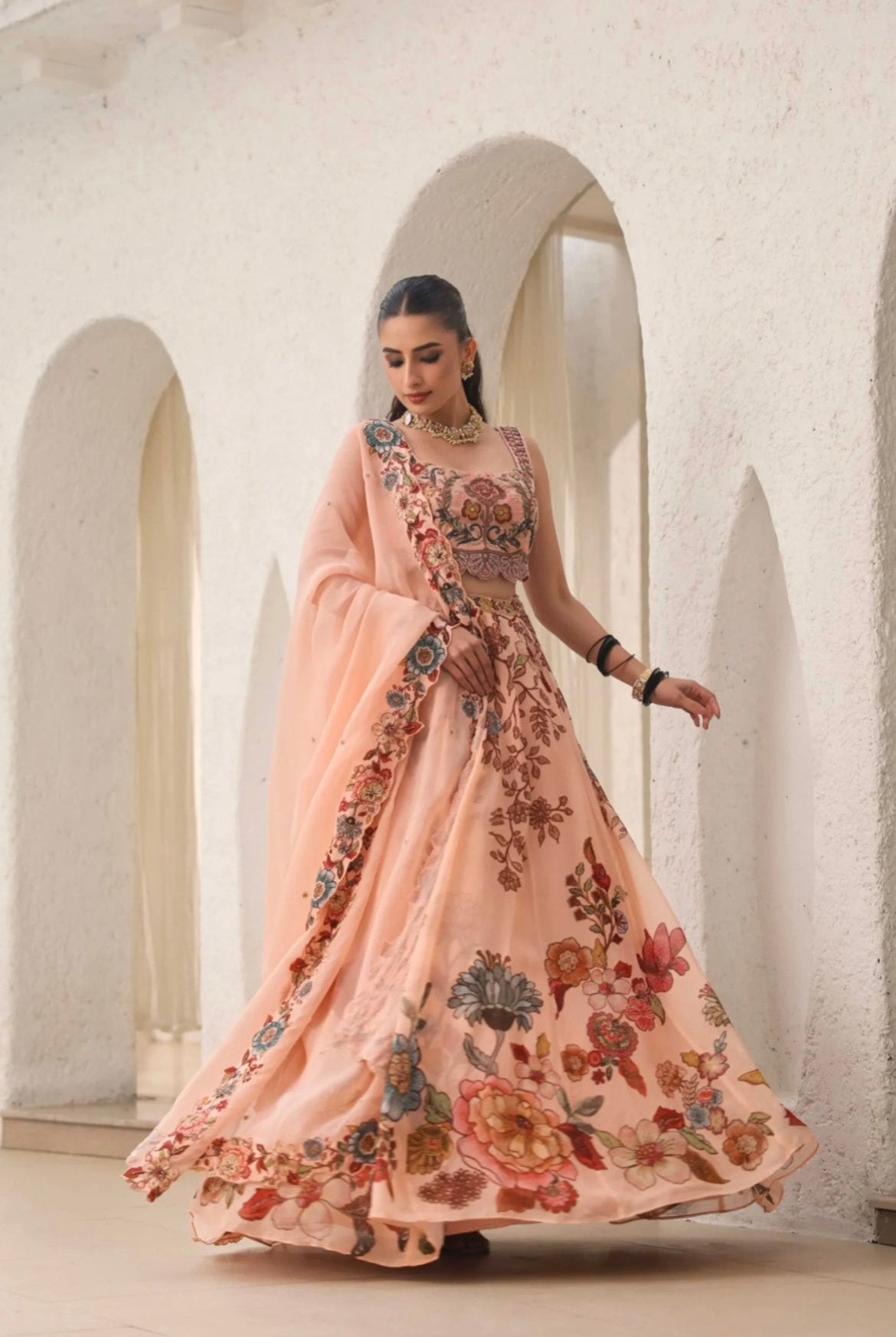 Lehenga choli for women. Peach colour made in Organza fabric with hand embroidery and print. Side View.