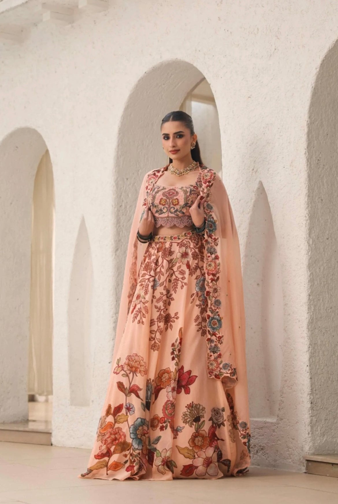 Lehenga choli for women. Peach colour made in Organza fabric with hand embroidery and print. Front View.