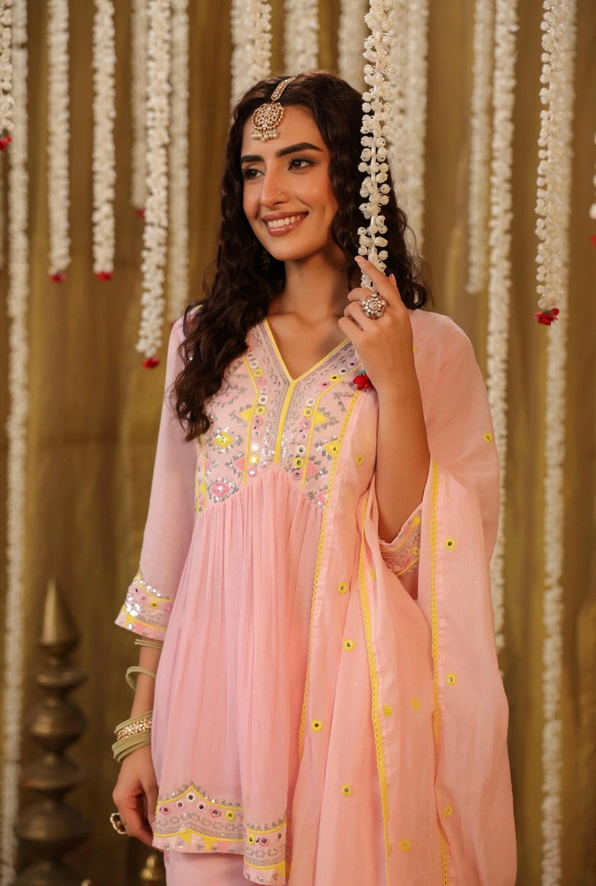 Cotton kurta peplum style in Baby Pink colour with sequins embroidery and intricate contrast yellow thread work. Accompanied by sharara pants. Upper half front view.