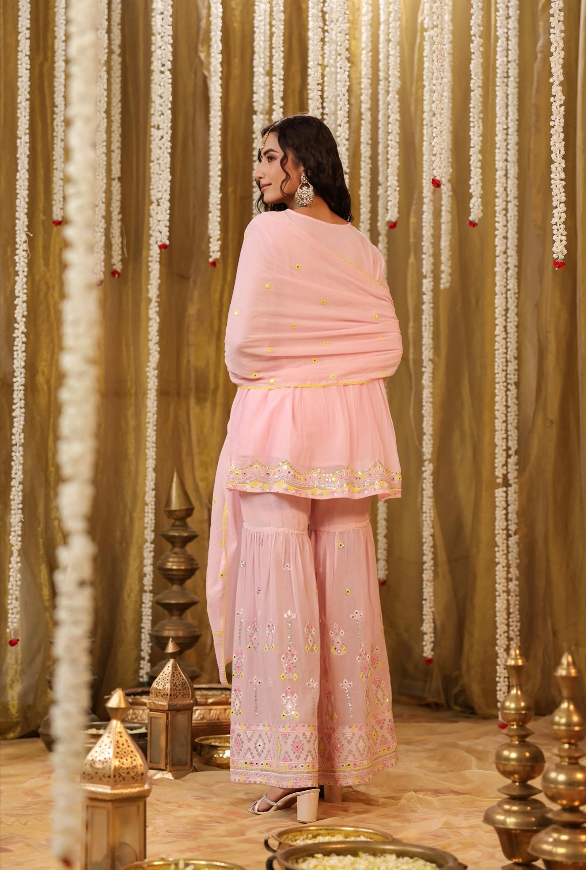 Cotton kurta peplum style in Baby Pink colour with sequins embroidery and intricate contrast yellow thread work. Accompanied by sharara pants. Back view.